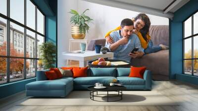 Young couple using a phone at home stock photo Wall mural