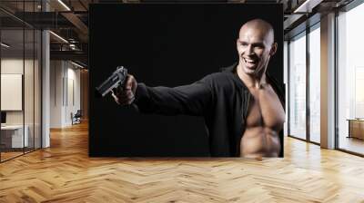 evil smiling man shooting gun isolated on black background Wall mural