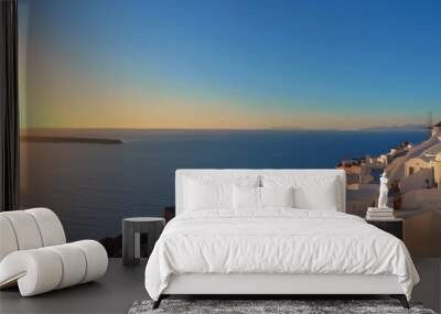 Sunset over Santorini island in Greece. Traditional church, apartments and windmills in Oia village. Wall mural