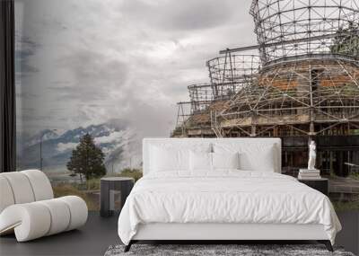 Side view of deserted dismantled cooling towers in the mountains with a cloudy sky and a road passing by, in landscape. Wall mural