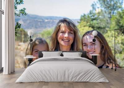 Smiling mother and daughters in natural light outdoors at park Wall mural