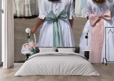 Dos niñas de primera comunión caminan con sus vestidos blancos con lazos. Wall mural