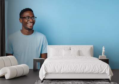 Attractive african american man wearing blue tshirt and glasses. Isolated on blue background. Wall mural