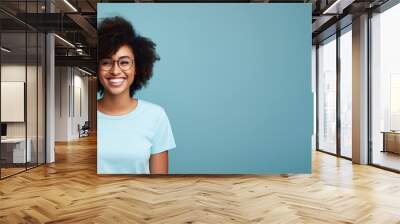 Attractive african american woman wearing blue tshirt and glasses. Isolated on blue background Wall mural