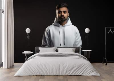 Handsome indian man with brown eyes wearing simple white hoodie. Isolated on dark background. Wall mural