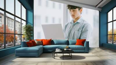 Asian businessman is using laptop to work by window Wall mural