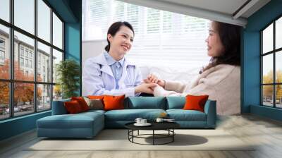 Asian female doctor examining an elderly woman at home Wall mural