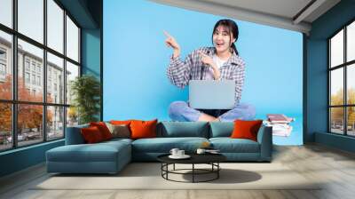 Asian female student with playful expression on blue background Wall mural