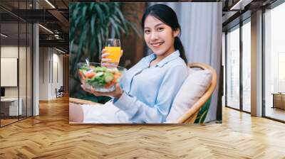 Beautiful young Asian woman enjoying breakfast with salad Wall mural