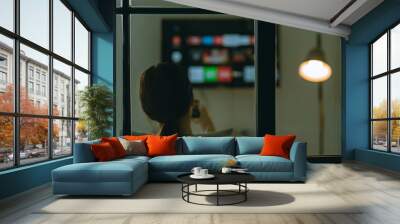 Blurry image of Asian woman sitting watching television alone on sofa at night Wall mural