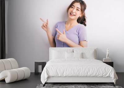 Cheerful young Asian girl pointing on white background Wall mural