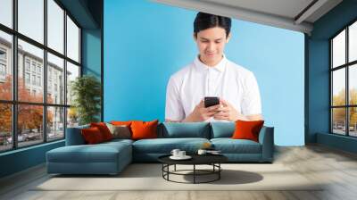 Closeup photo of young man looking at screen of smart phone, smiling nicely while chatting with friend Wall mural