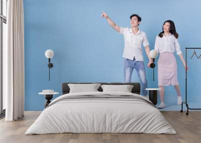 Full length image of young Asian couple on blue background Wall mural