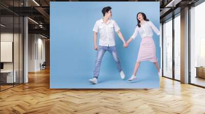 Full length image of young Asian couple on blue background Wall mural