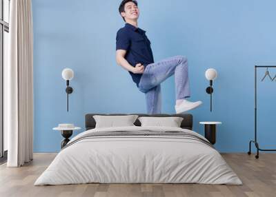 Full length image of young Asian man posing on blue background Wall mural