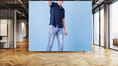 Full length image of young Asian man posing on blue background Wall mural