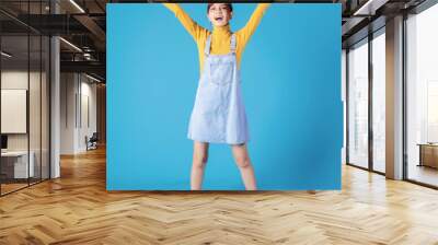 Full length photo of young Asian girl standing on blue background Wall mural