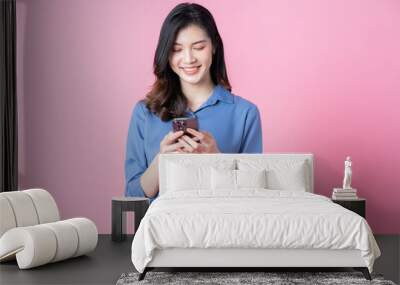 Image of young Asian business woman using smartphone on pink background Wall mural