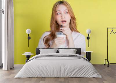 Image of young Asian girl drinking milk tea on yellow background Wall mural