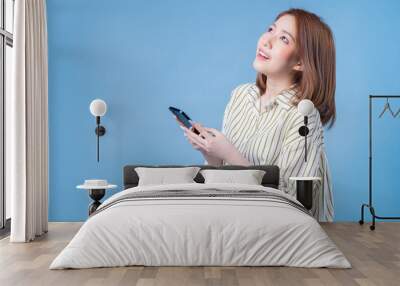 Image of young Asian girl using smartphone on blue background Wall mural