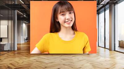 Image of young Asian girl wearing yellow t-shirt on orange background Wall mural