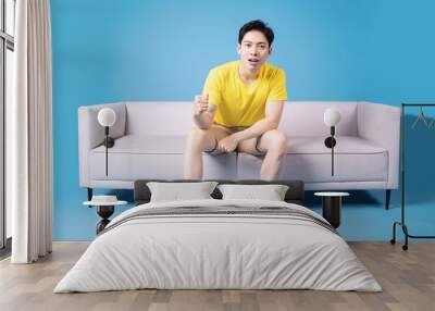 Image of young Asian man sitting on sofa Wall mural