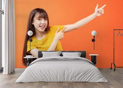 Image of young Asian woman wearing yellow t-shirt on orange background Wall mural