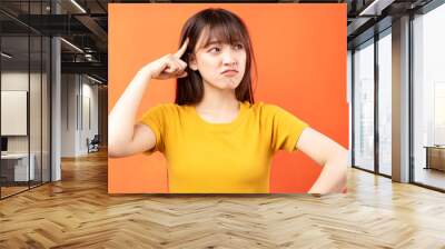 Image of young Asian woman wearing yellow t-shirt on orange background Wall mural