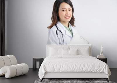 Portrait of asian female doctor standing smiling on white background Wall mural