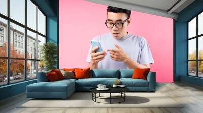 Portrait of Asian man using smartphone on pink background Wall mural