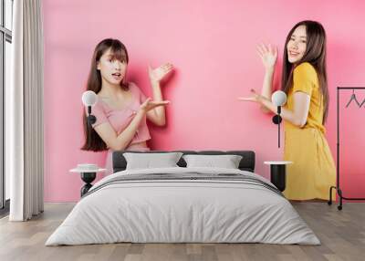 Portrait of two beautiful young Asian girls posing on pink background Wall mural