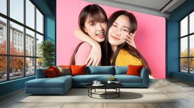 Portrait of two beautiful young Asian girls posing on pink background Wall mural