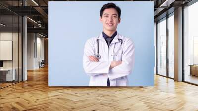 Portrait of young Asian male doctor on blue background Wall mural