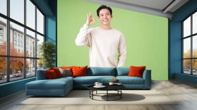 Portrait of young Asian man posing on green background Wall mural