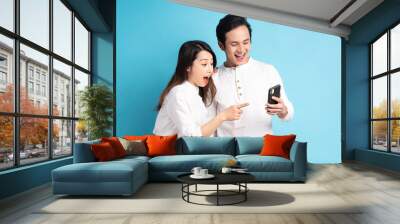 Portrait of young couple using phone on background Wall mural