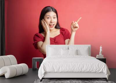 Portrait of young girl wearing red dress with expression on background Wall mural