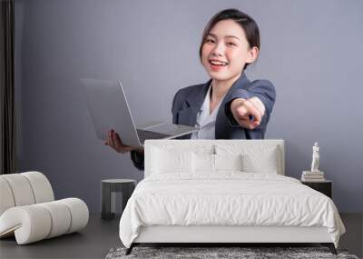 Young Asian business woman wearing suit and using laptop on gray baclground Wall mural