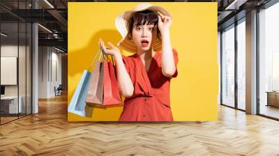 Young Asian businesswoman holding shopping bags posing on yellow background Wall mural