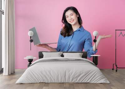 Young Asian businesswoman using laptop on pink background Wall mural