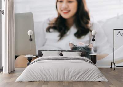 Young Asian businesswoman working and playing with cat Wall mural