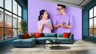 Young Asian couple using smartphone on purple background Wall mural