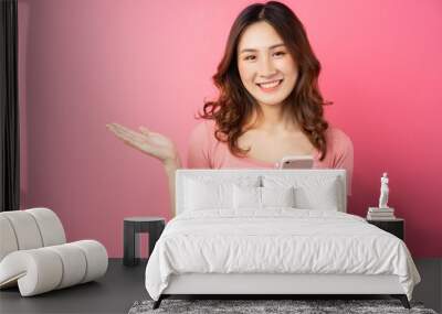 Young asian girl using the phone on pink background Wall mural