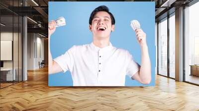 Young Asian man holding money on background Wall mural