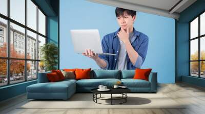 Young Asian man using laptop on blue background Wall mural