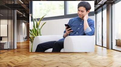 Young Asian man using the phone in the living room Wall mural