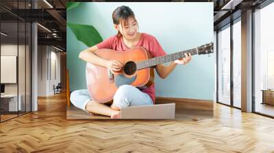 Young Asian woman learning guitar at home Wall mural