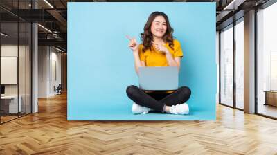 Young girl sitting using laptop with expressions and gestures on background Wall mural