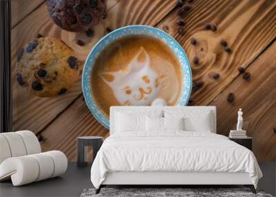 Cat foam face of latte art coffee in cup with scattered coffee beans and biscuits on old wooden table Wall mural