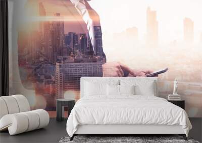 The double exposure image of the business man using a smartphone during sunrise overlay with cityscape image. The concept of modern life, business, city life and internet of things. Wall mural