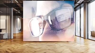 The double exposure image of the businessman's eyes wear a glasses during sunrise overlay with cityscape image. The concept of modern life, business, city life and internet of things. Wall mural